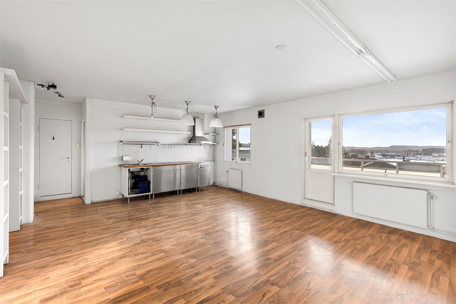 Et lyst og åpent allrom med store vindusflater danner leilighetens midtpunkt.