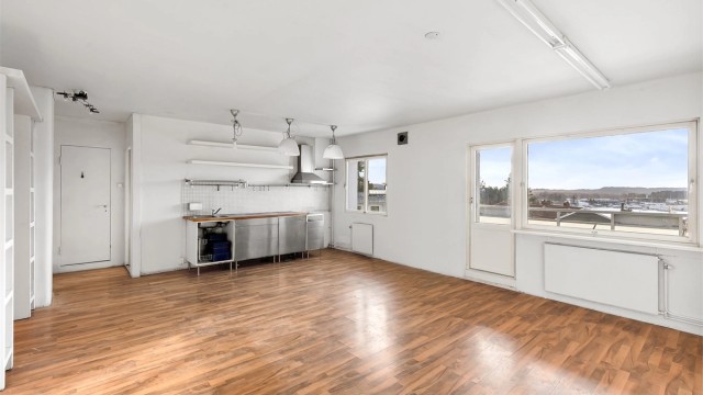 Et lyst og åpent allrom med store vindusflater danner leilighetens midtpunkt.