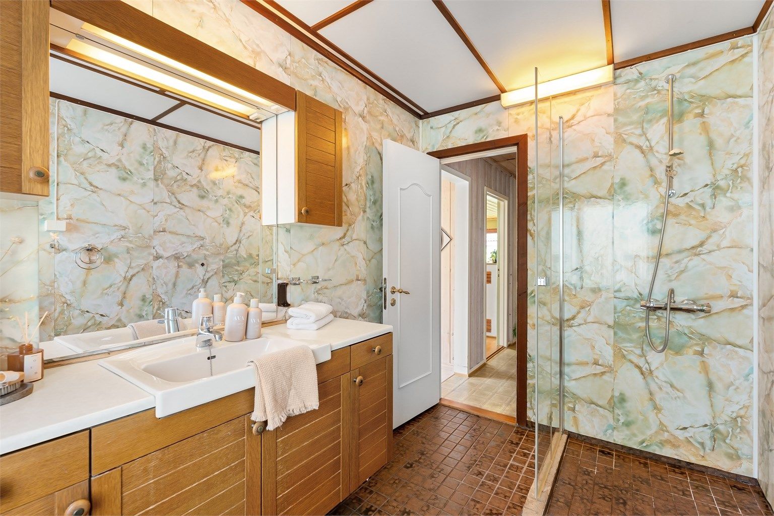 Badet er innredet med dusjhjørne med glassdør.