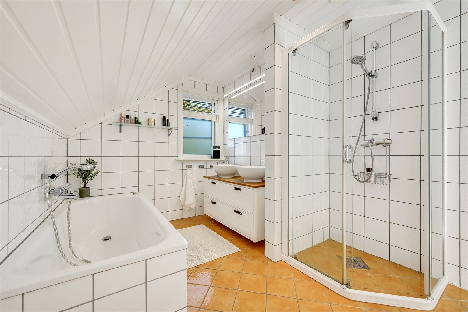 Badet i 2. etasje har fliser, gulvvarme, innfliset badekar og separat dusjhjørne.