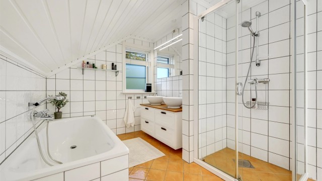 Badet i 2. etasje har fliser, gulvvarme, innfliset badekar og separat dusjhjørne.