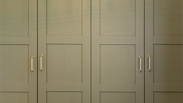 Den lekre garderobeløsningen i dempet olivengrønt med elegante messinghåndtak er et flott blikkfang. Skapene med profilerte dører gir praktisk oppbevaring i full høyde, og tilfører rommet både karakter og varme.