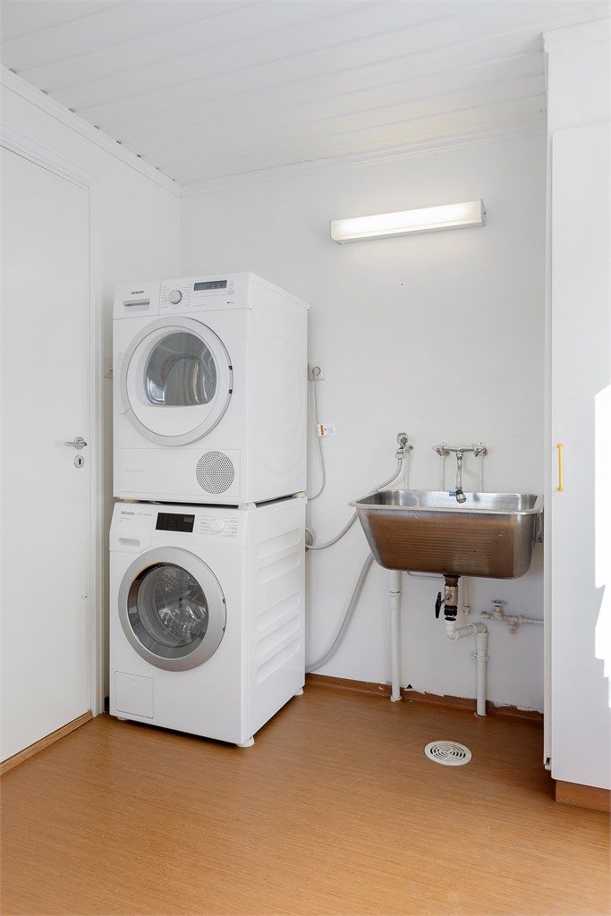 Praktisk vaskerom med utslagsvask, opplegg for vaskemaskin og utgang til en østvendt terrasse på ca. 14 m².