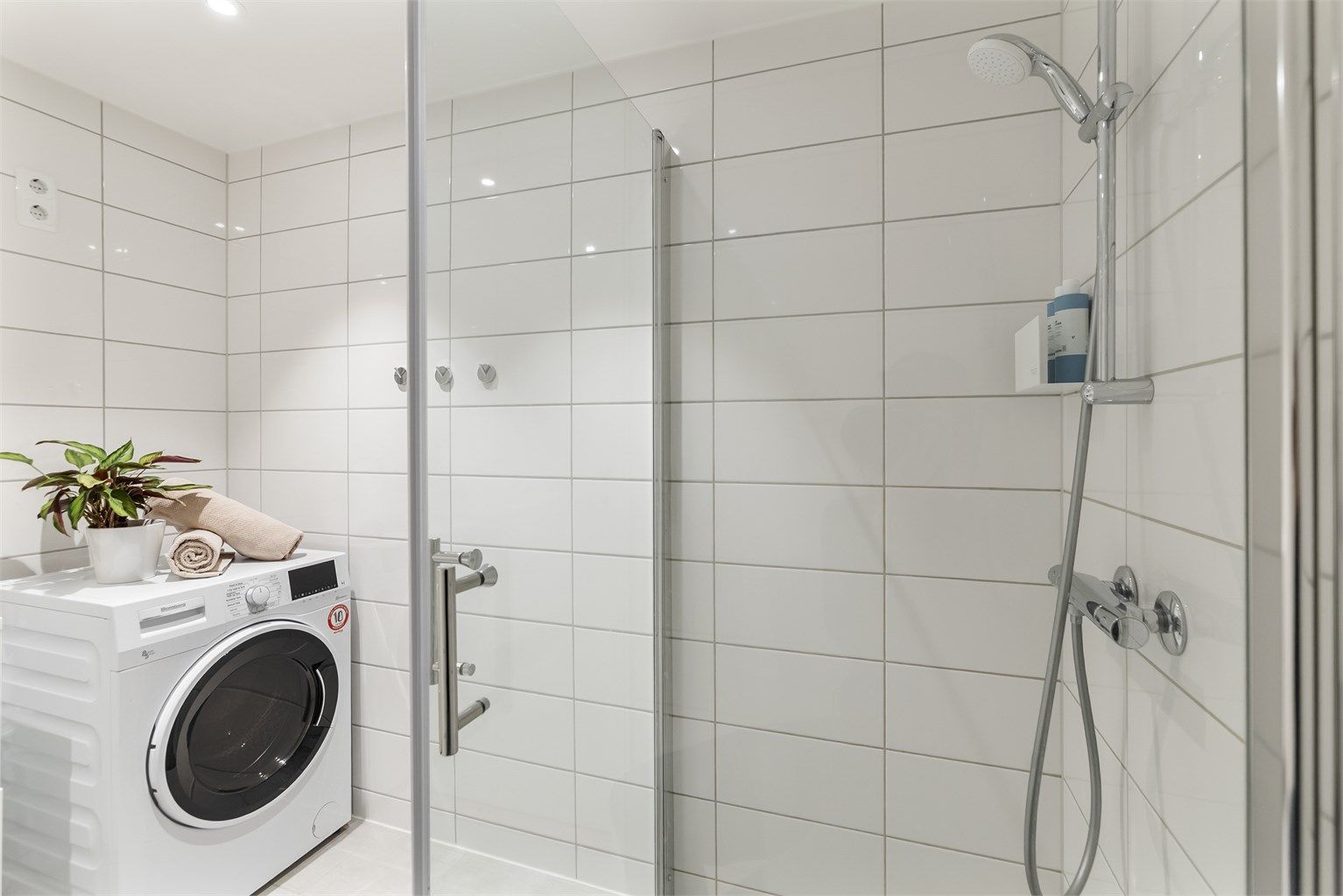 Badet er innredet med vegghengt klosett, servant med innredning, speil med lys og dusjhørne med svingbare dusjdører