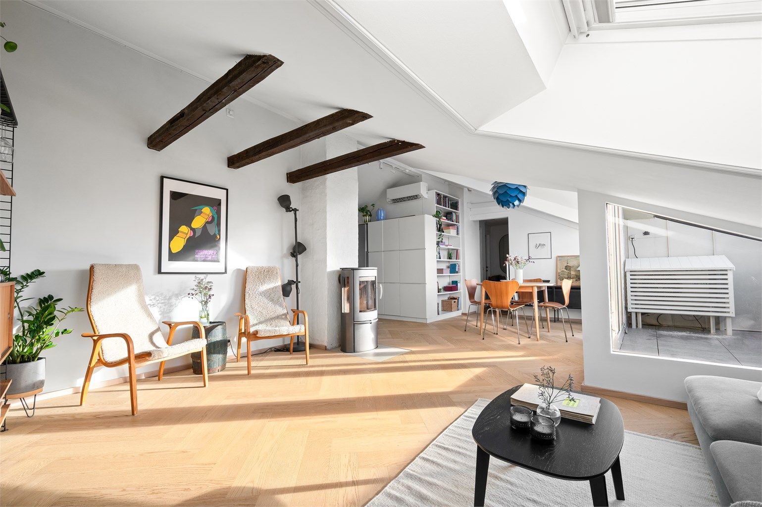 Synlige takbjelker gir rommet karakter og understreker den åpne følelsen mot spiseplass og kjøkken.