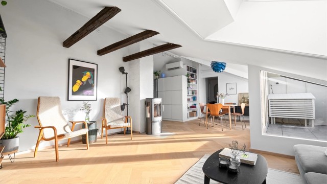 Synlige takbjelker gir rommet karakter og understreker den åpne følelsen mot spiseplass og kjøkken.