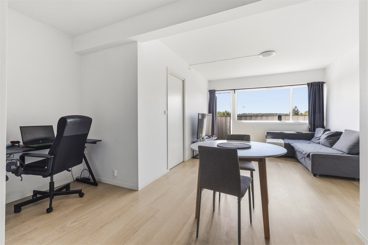 Lys og romslig stue med store vindusflater og god plass til både spisebord og sofagruppe.