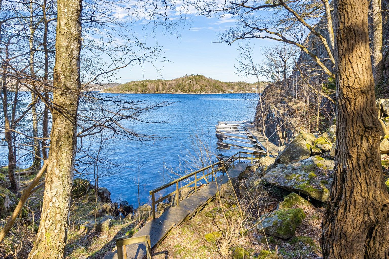 En sti med trapper i tre leder ned til bryggeanlegget og båtplassen. Badestige er det også på brygga.