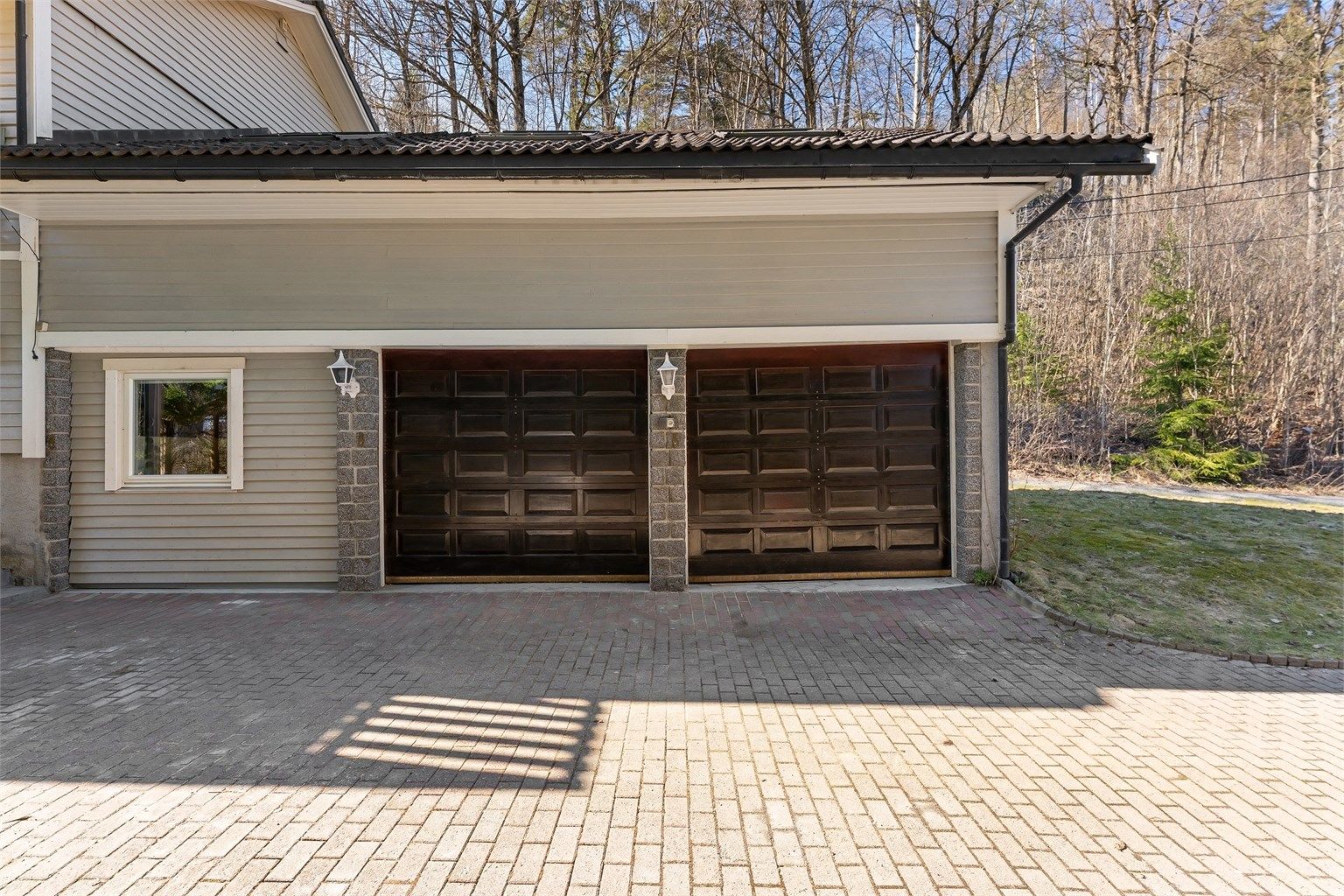 Garasjen er tilliggende boligen, med elektriske leddporter i tre. Rom over garasje er godkjent i kommunen og kjøper overtar ansvaret for dette. Konsekvens er at det må rives.