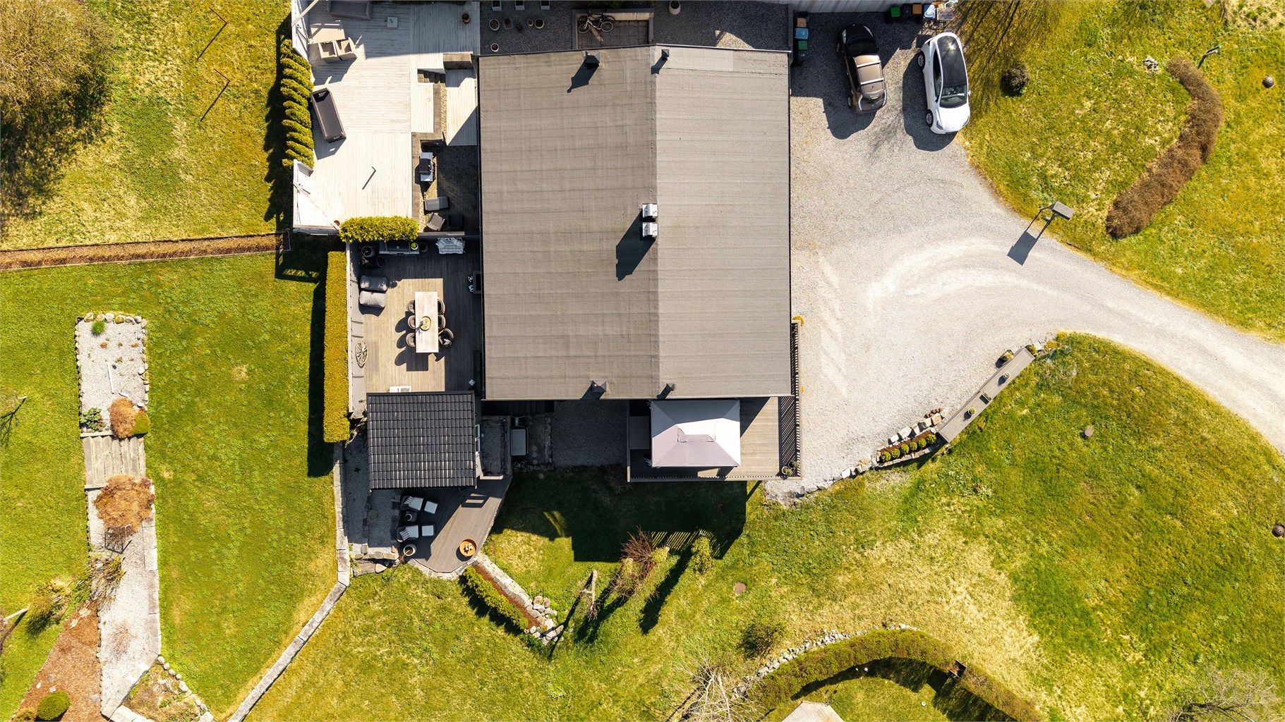 Tomten er opparbeidet med gruslagt gårdsplass, plenarealer og beplantning