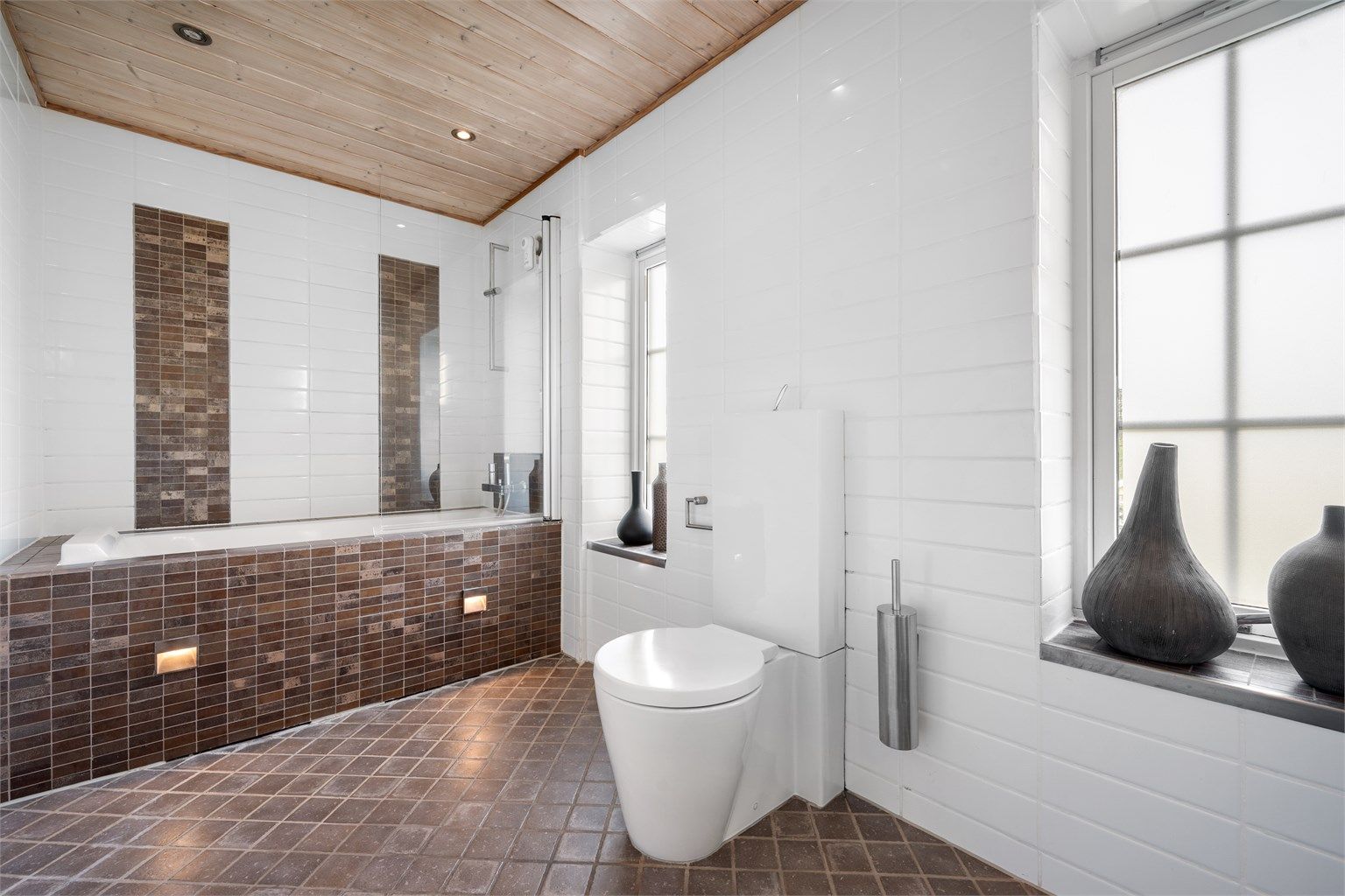 Badet har downlights i taket og et rør-i-rør-system med fordelerskap på veggen.