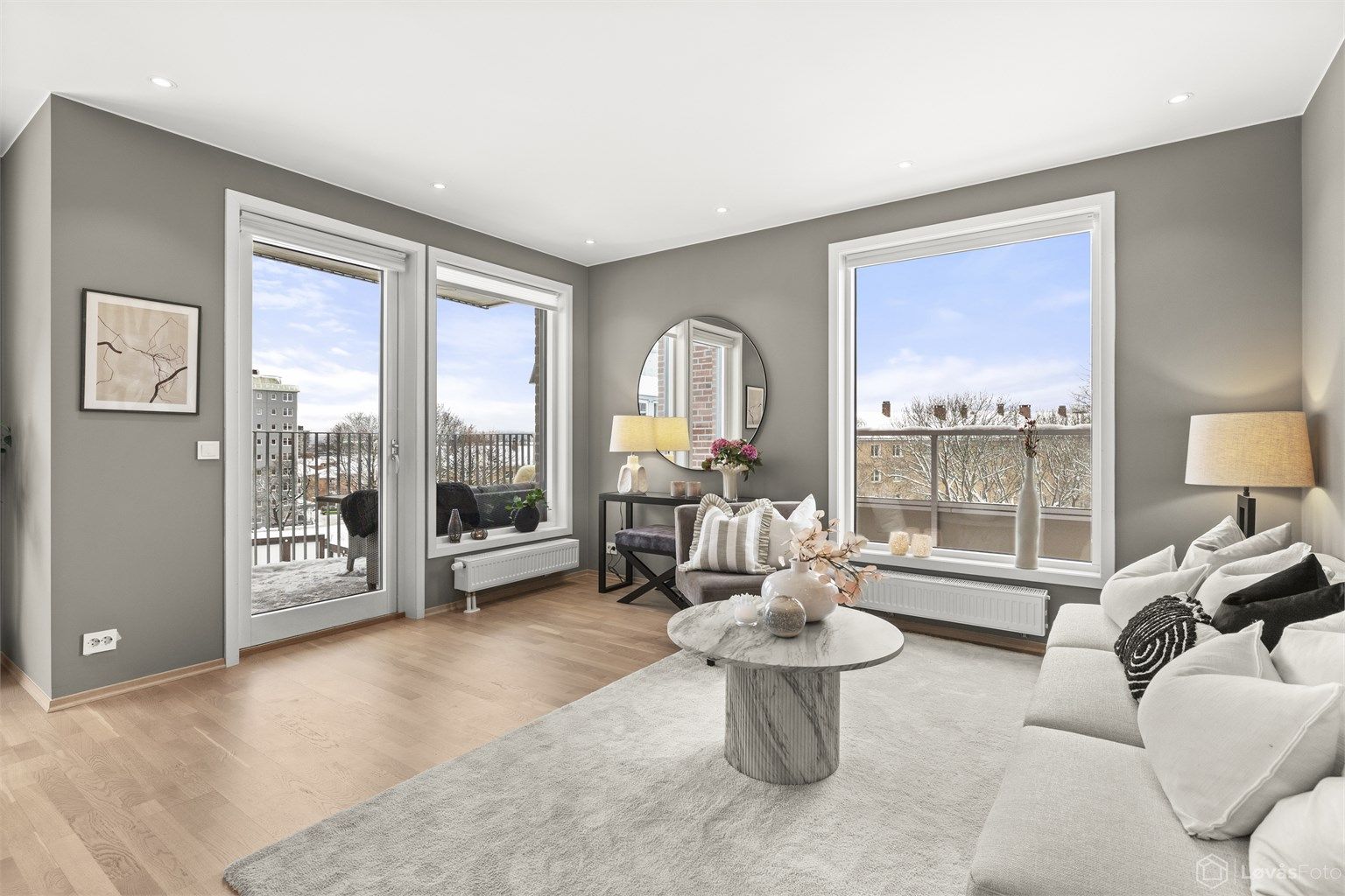 Store vindusflater og utgang til balkong gir rommet en luftig atmosfære.