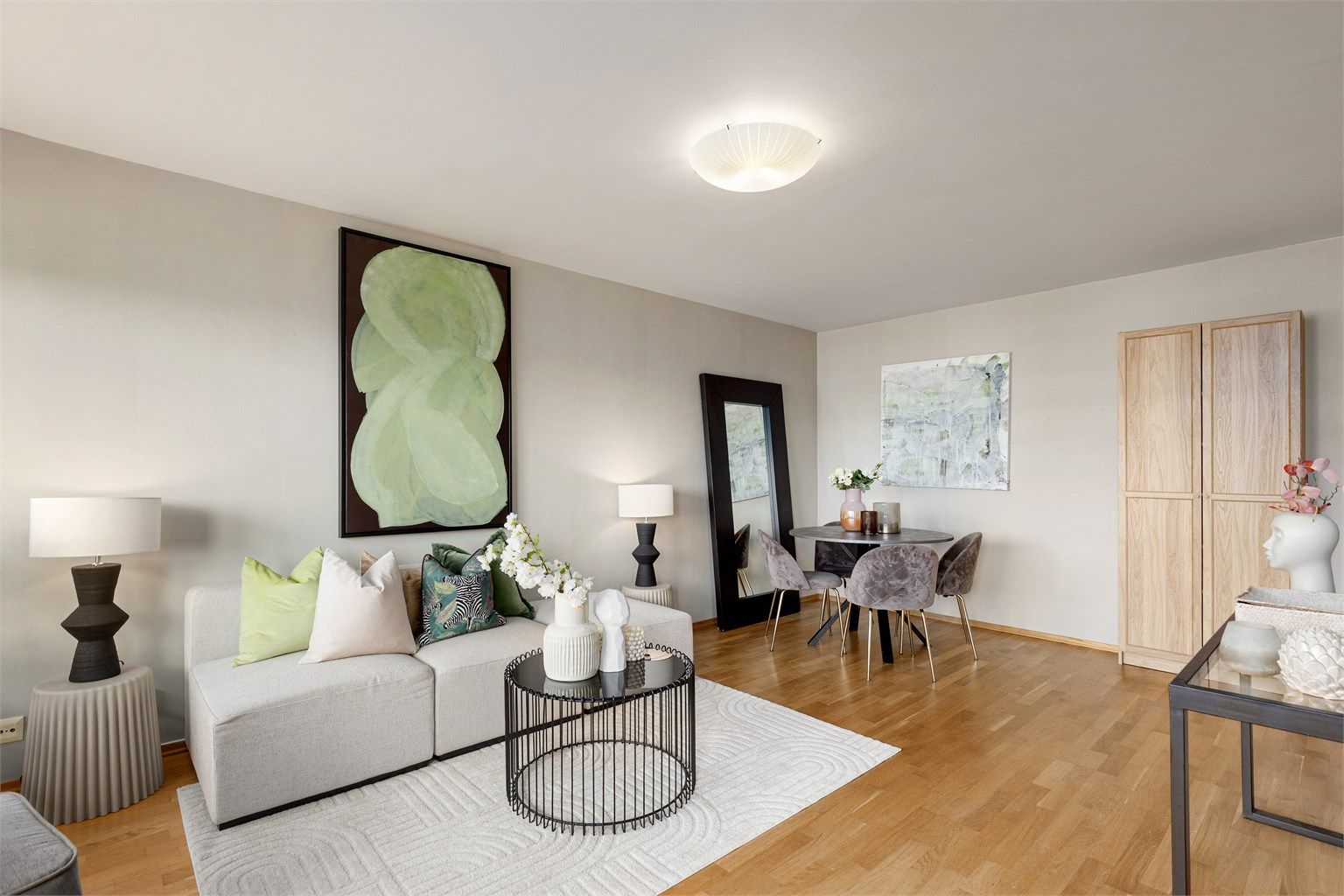 Romslig stue med god plass til både sofagruppe med stuebord og TV-benk på den ene siden, samt spisebord og vitrineskap på motsatt side