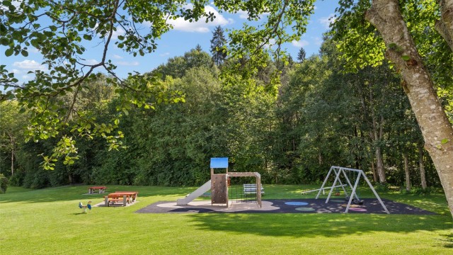 Store, grønne fellesarealer med lekeplass rett utenfor bygget.