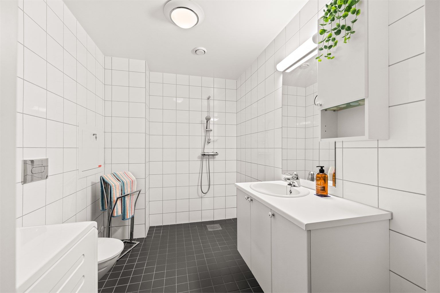 Badet i denne leiligheten har innredning fra Sigdal, vegghengt toalett og praktisk dusjhjørne.