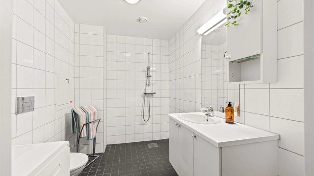 Badet i denne leiligheten har innredning fra Sigdal, vegghengt toalett og praktisk dusjhjørne.