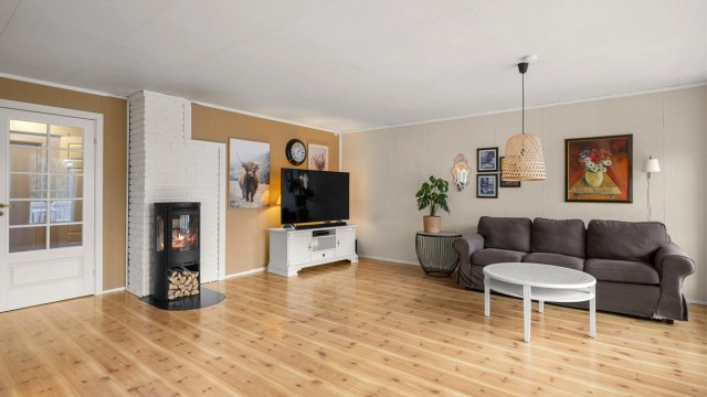 Stuen fremstår som luftig og innbydende, med vedovn som skaper en lun og hyggelig atmosfære gjennom kjøligere dager.