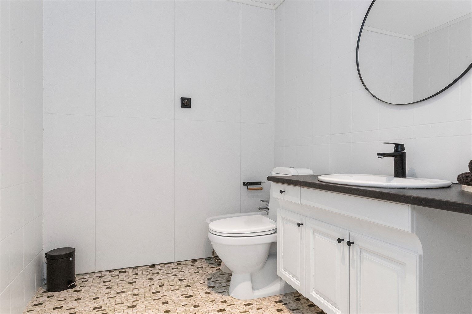 Et lyst og funksjonelt bad med mosaikkfliser på gulvet.