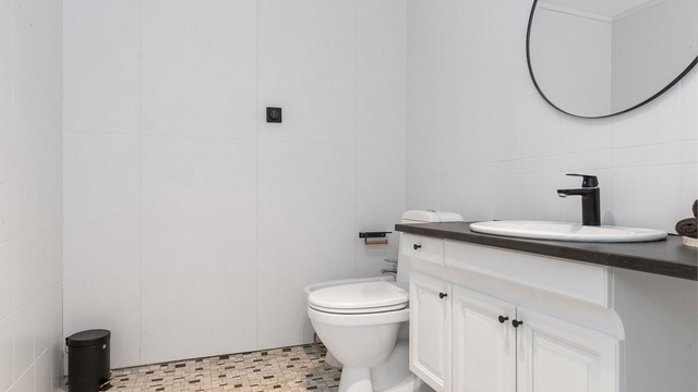 Et lyst og funksjonelt bad med mosaikkfliser på gulvet.