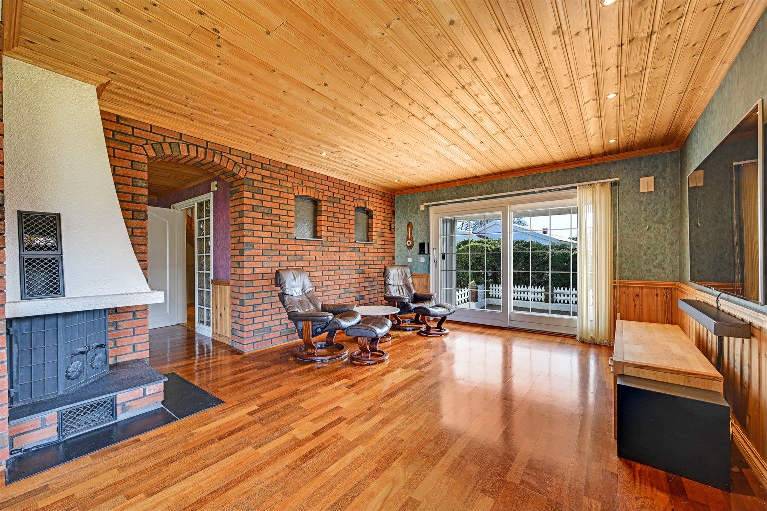 Stuen har en peis med innsats som gir god varme, og en skyvedør i tre ut til terrassen.