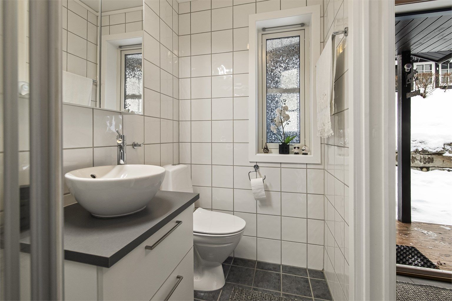 Badet er innredet med toalett, dusjhjørne og servant i innredning