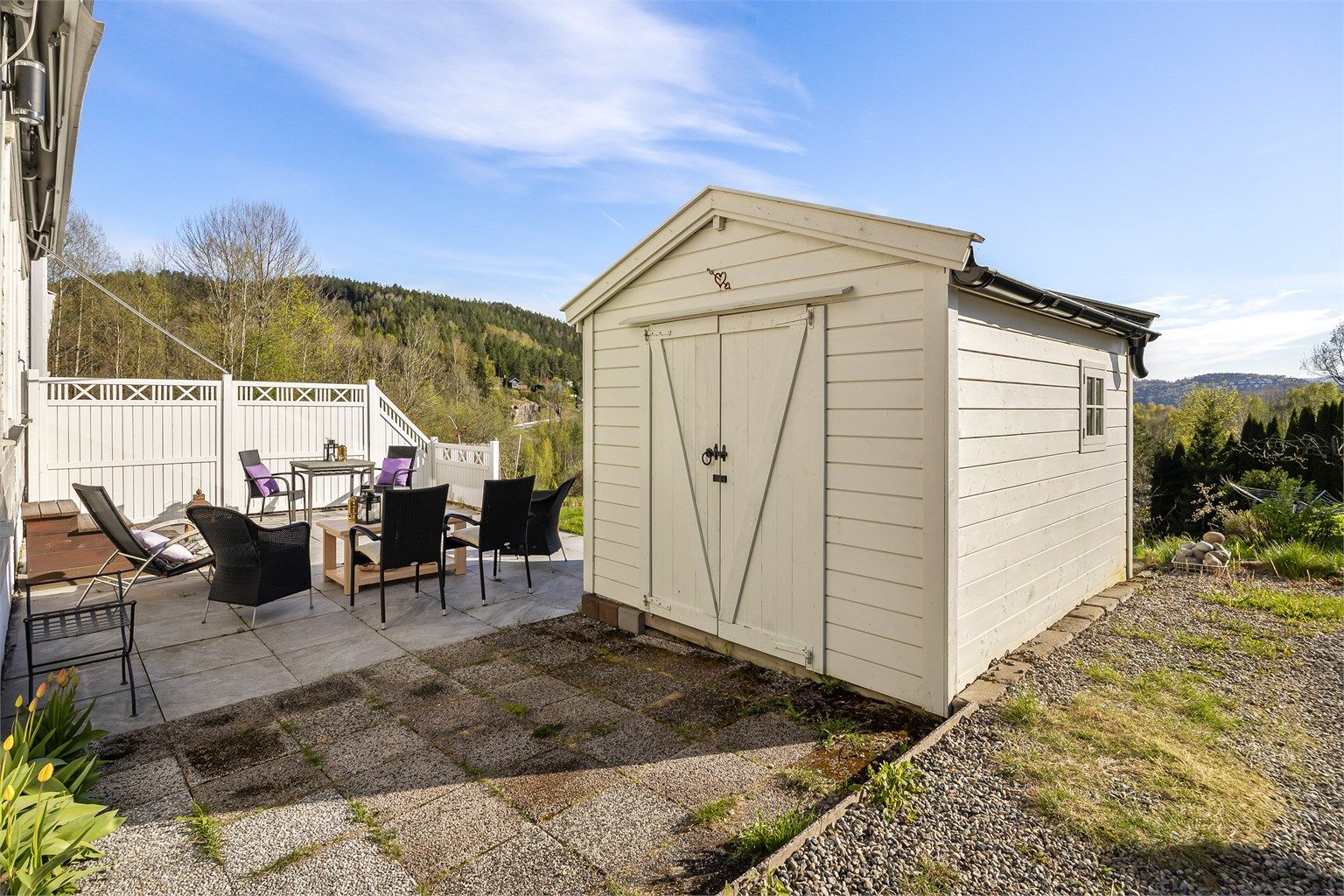 Uteområdet er opparbeidet med grus, plen og en romslig, flislagt terrasse.