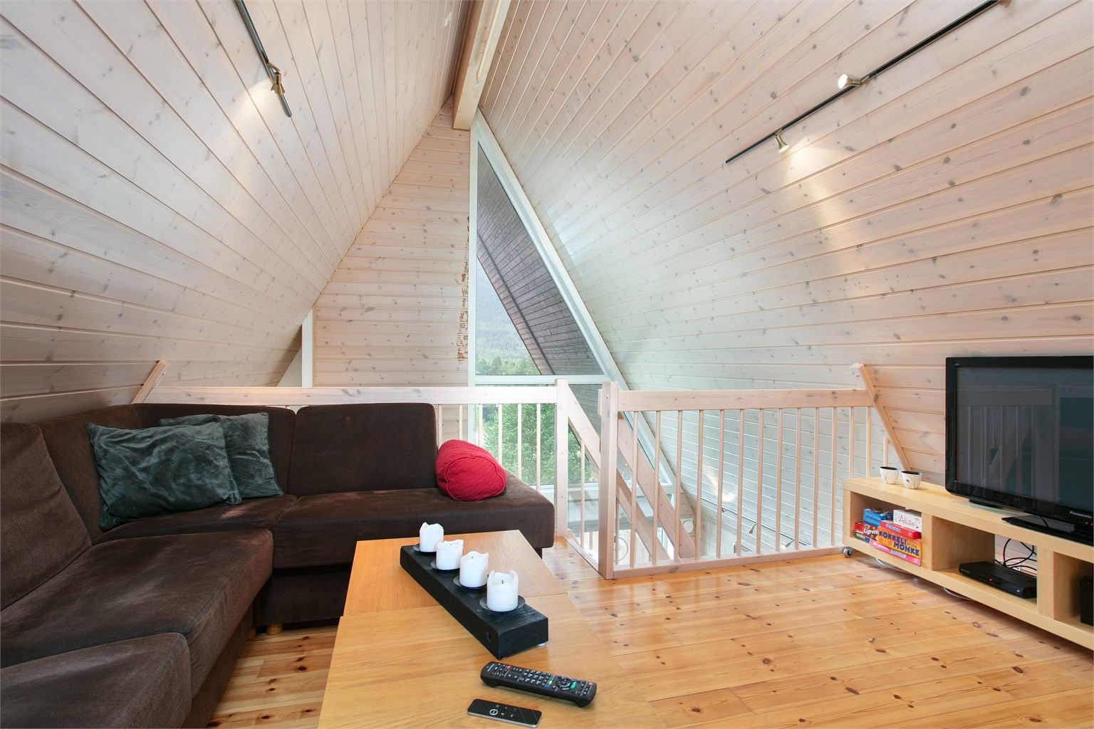 Loftstue på hemsen med panelte skråhimlinger og åpen utsikt ned mot stuen.