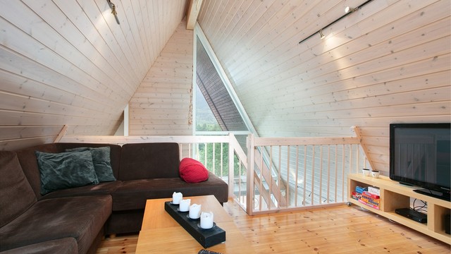 Loftstue på hemsen med panelte skråhimlinger og åpen utsikt ned mot stuen.