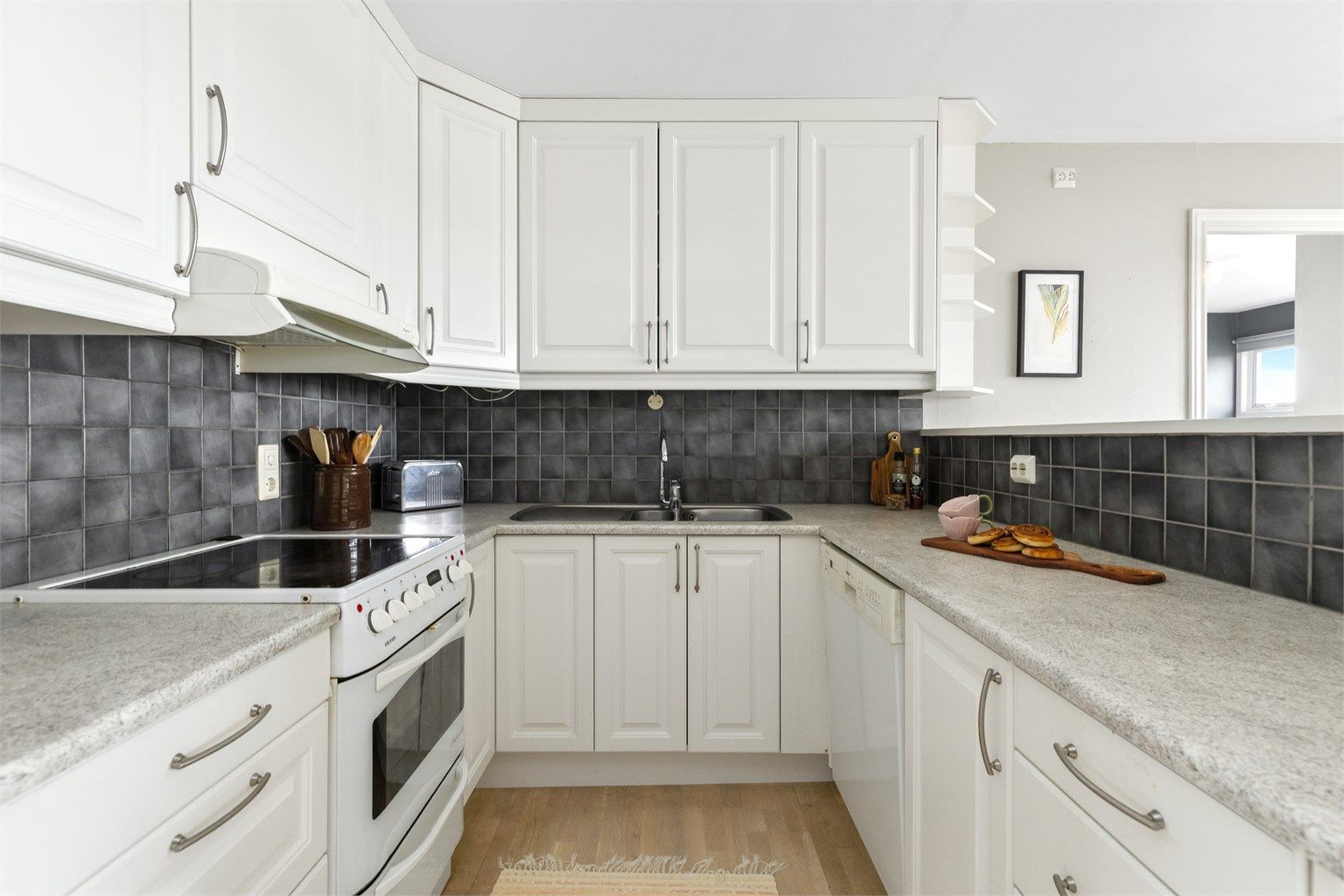 Kjøkkeninnredning med profilerte fronter, laminatbenkeplate og godt med oppbevaringsplass.