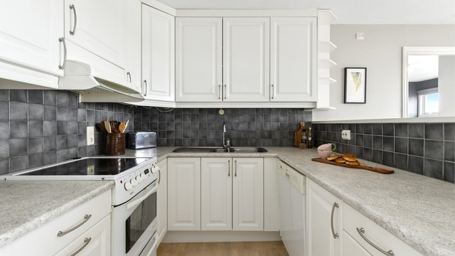 Kjøkkeninnredning med profilerte fronter, laminatbenkeplate og godt med oppbevaringsplass.