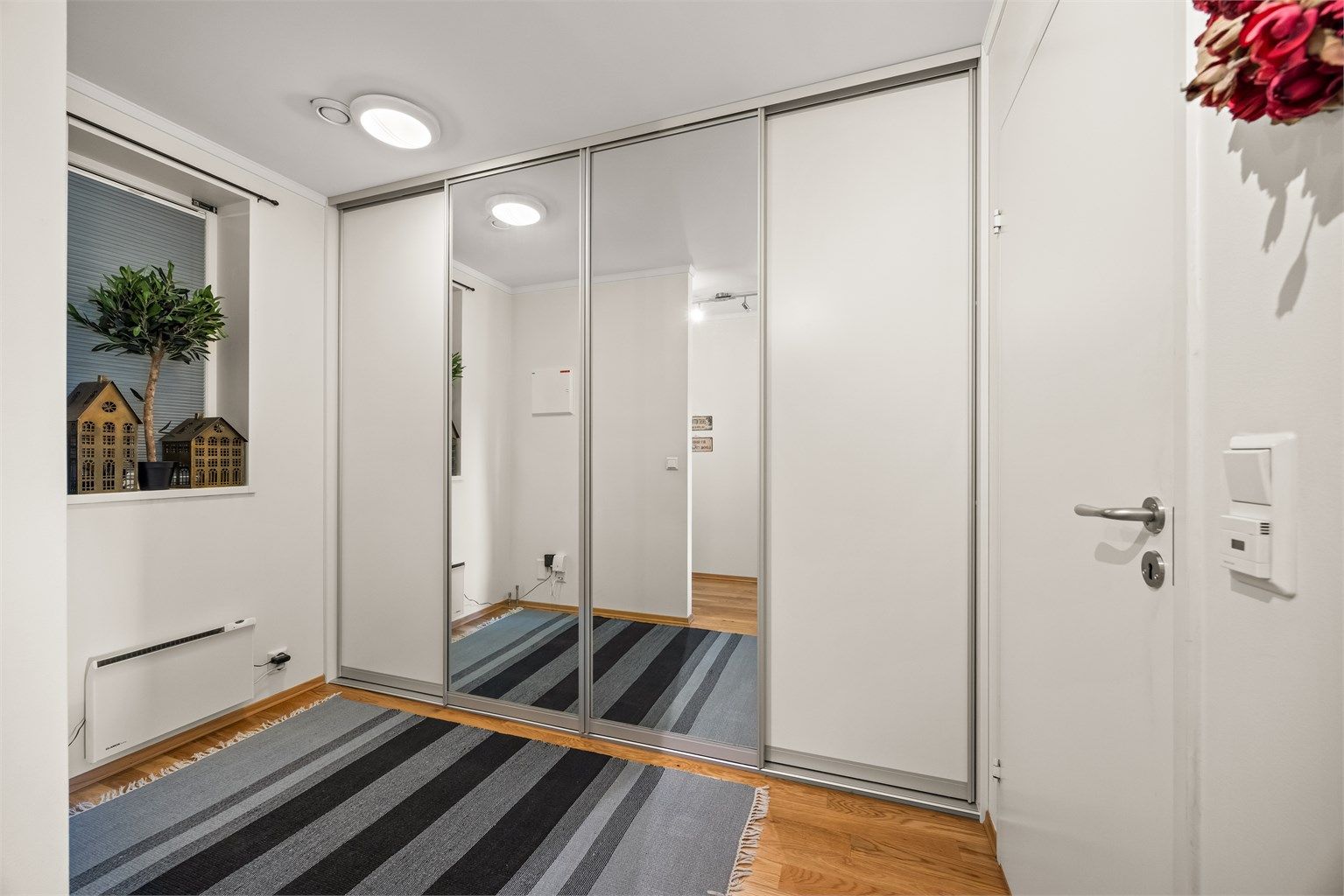 Romslig skyvedørsgarderobe med speilfronter gir rikelig med oppbevaringsplass i entréen.