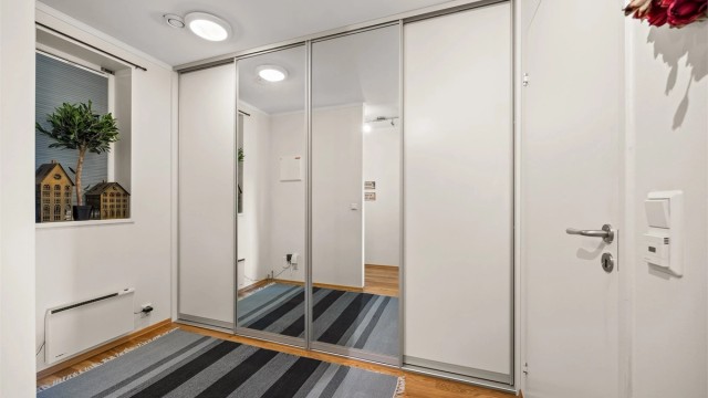 Romslig skyvedørsgarderobe med speilfronter gir rikelig med oppbevaringsplass i entréen.