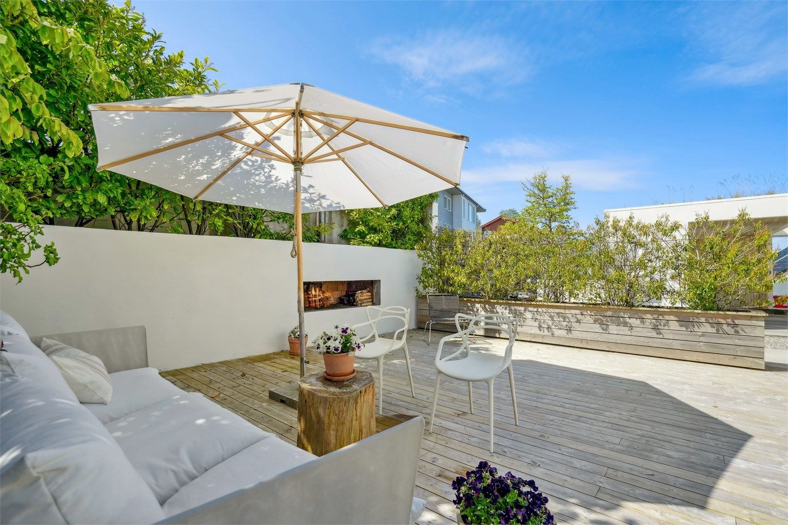 Skjermet terrasse i tre med flott utepeis. Terrassen har gode solforhold og har skyvedør fra kjøkken