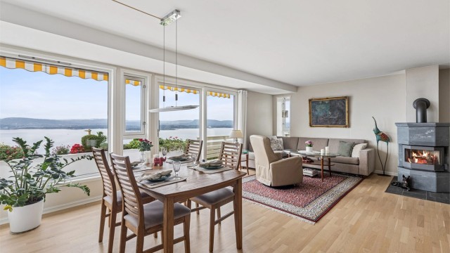 Lys og innbydende stue der store vindusflater gir rikelig med lys og åpner rommet fullstendig mot utsikten.