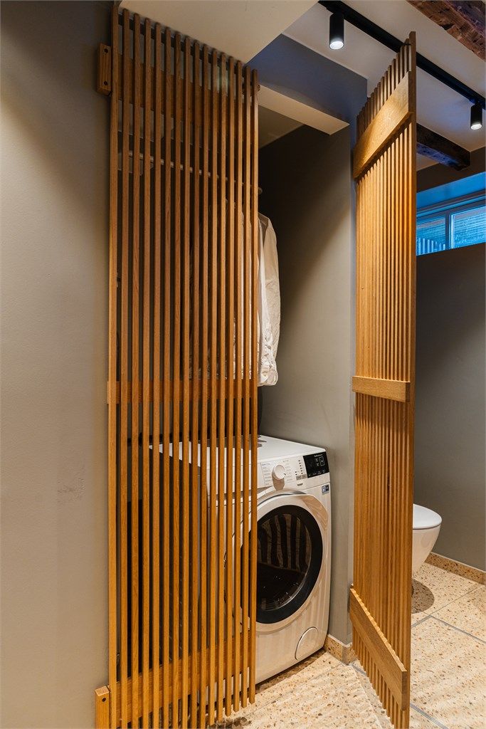 Bak spiledører i tre er det praktisk opplegg for vaskemaskin.