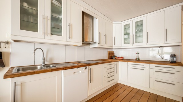 Kjøkkeninnredning med profilerte fronter, benkeplate i tre og integrert platetopp. Kjøkkenets plassering avviker fra godkjente byggetegninger. Opprinnnelig lå vaskerommet og innvendig bod her. Foto: Martine Eren Jacobsen