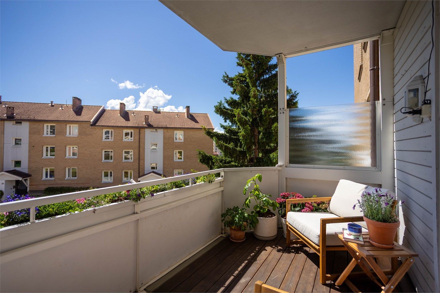 Balkonggulvet har terrassebord i tre, og rekkverket er i stål og fasadeplater.