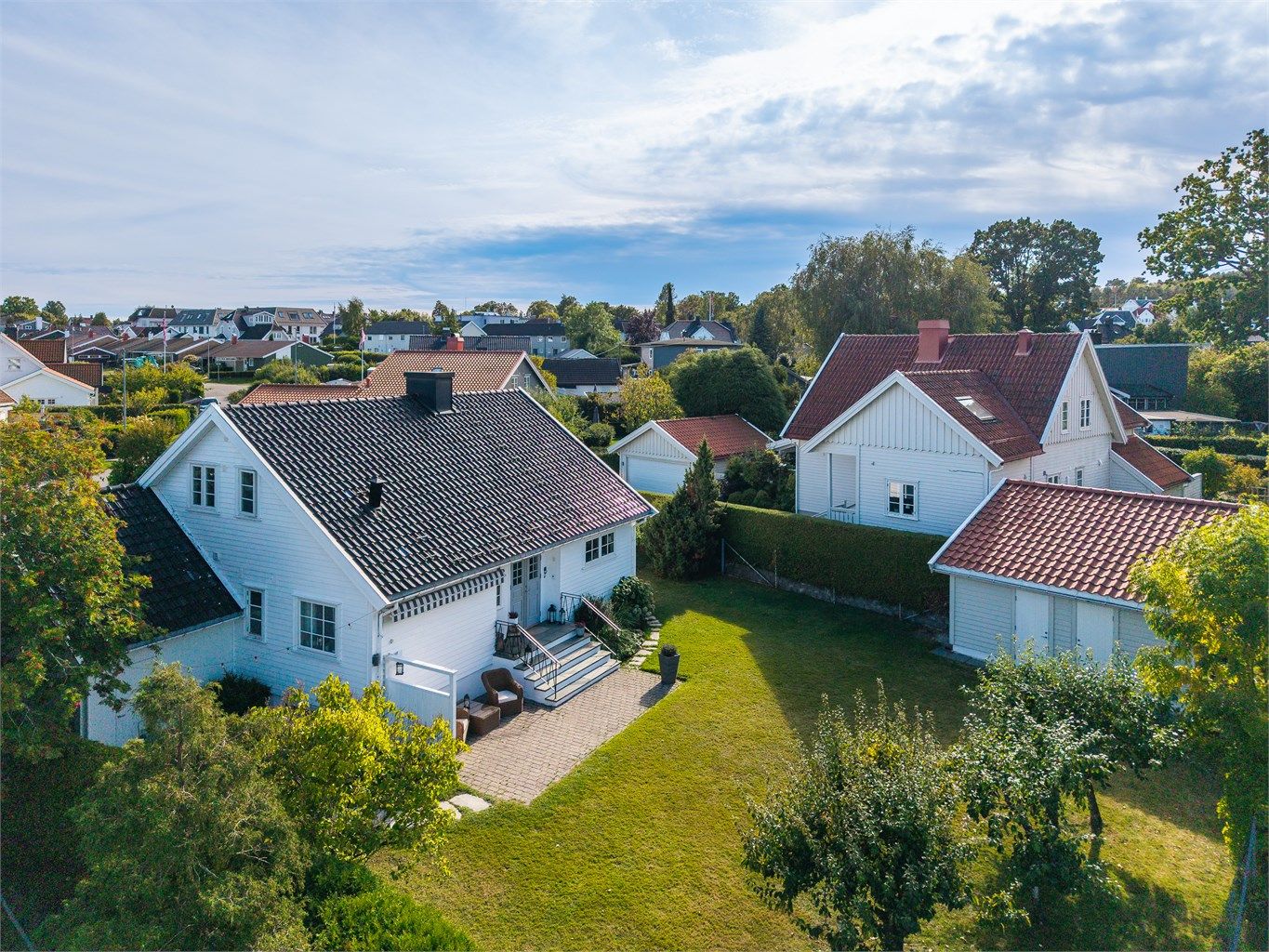 Romslig tomt med gjerde og hekk som rammer inn eiendommen.