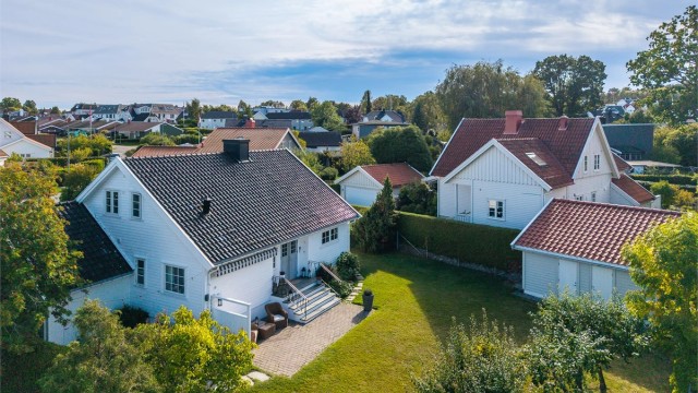 Romslig tomt med gjerde og hekk som rammer inn eiendommen.