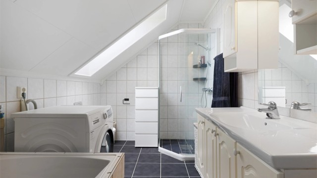 Pent flislagt bad på 6 kvm med gulvvarme, downlights og opplegg for vaskemaskin. Videre er badet utstyrt med servantskap med overskap og speil med lys, vegghengt toalett, dusjhjørne og badekar.