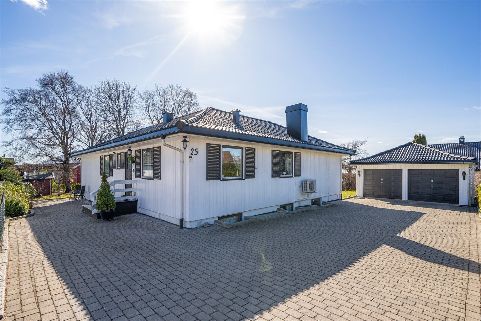Belegningsstein på gårdsplassen og innkjørselen fører til en frittliggende dobbelgarasje på 45 m², bygget i 1990.