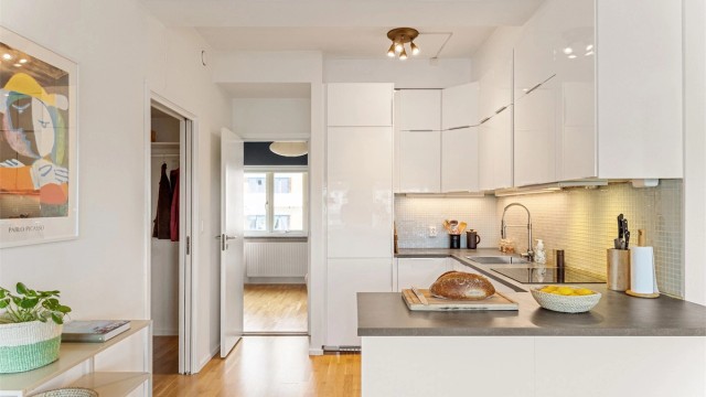 Kjøkkenet har en lys og tidløs innredning med hvite, glatte fronter og integrerte hvitevarer som gir et rent og harmonisk uttrykk.