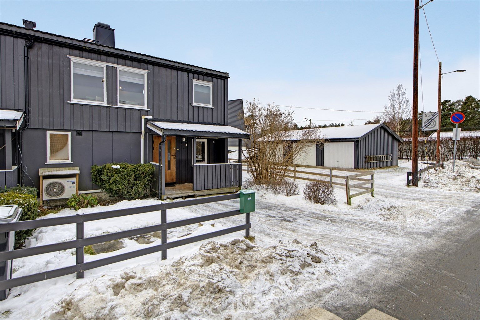 Fasade ved inngangsparti - overbygget inngangsparti - plass til parkering på egen gårdsplass og i felles garasjerekken (i garasjerekken som sees til høyre i bildet)