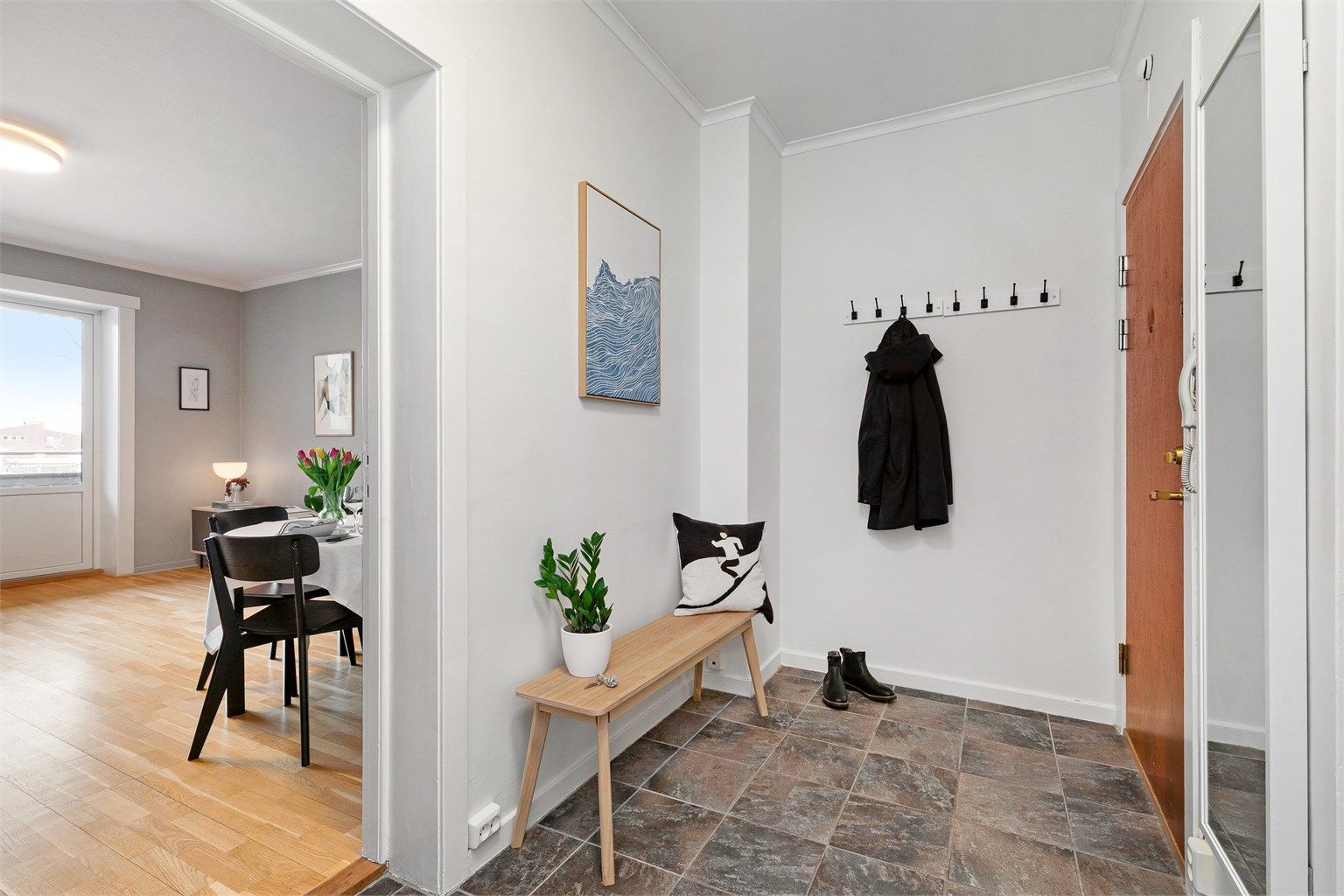 Lys entré med flislagt gulv. Her er det plass til å henge fra yttertøy på vegghengte knagger samt plass til en sittebenk eller hylle/garderobeskap.