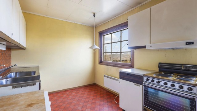 Kjøkken med innredning med glatte fronter og laminert benkeplate med nedfelt oppvaskkum i rustfritt stål.