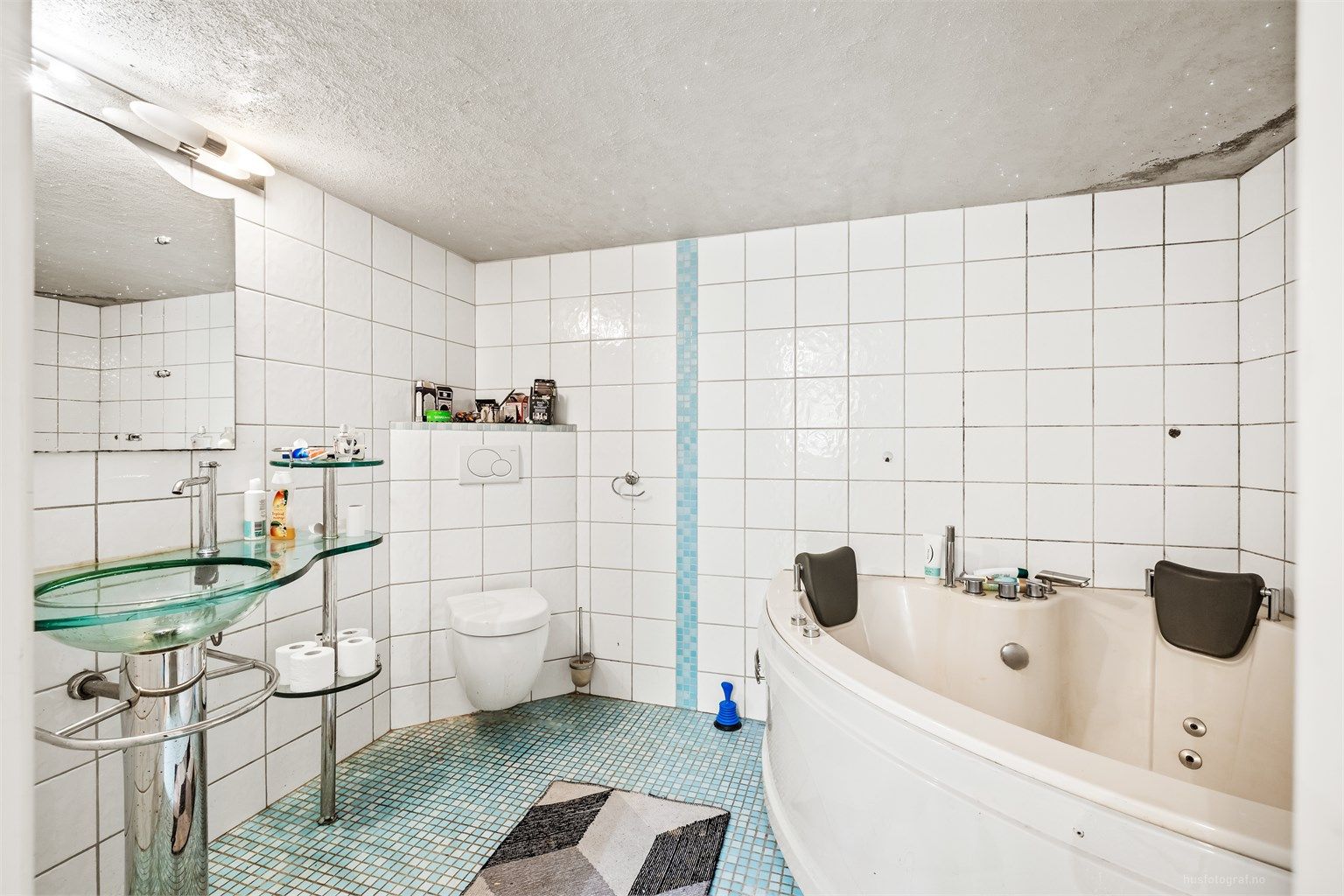 Badet i kjelleren har flislagte overflater, gulvvarme og badekar - Hybel.