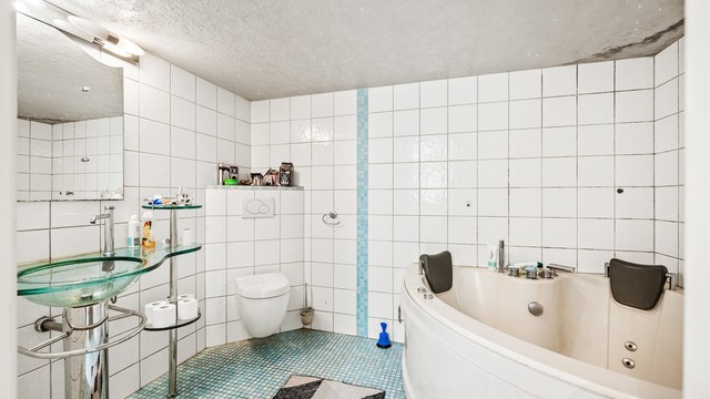 Badet i kjelleren har flislagte overflater, gulvvarme og badekar - Hybel.