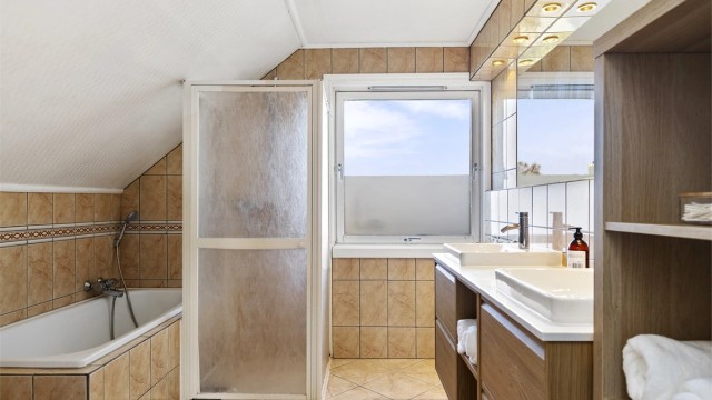 Romslig, flislagt bad i andre etasje med både badekar og dusjløsning.