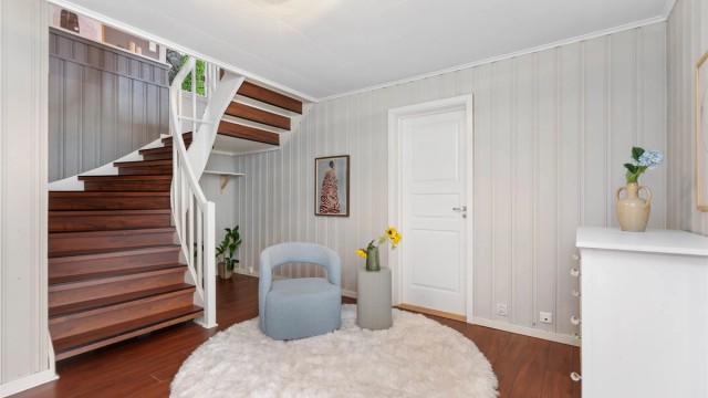 Romslig hall i underetasjen med trapp opp til hovedetasjen.