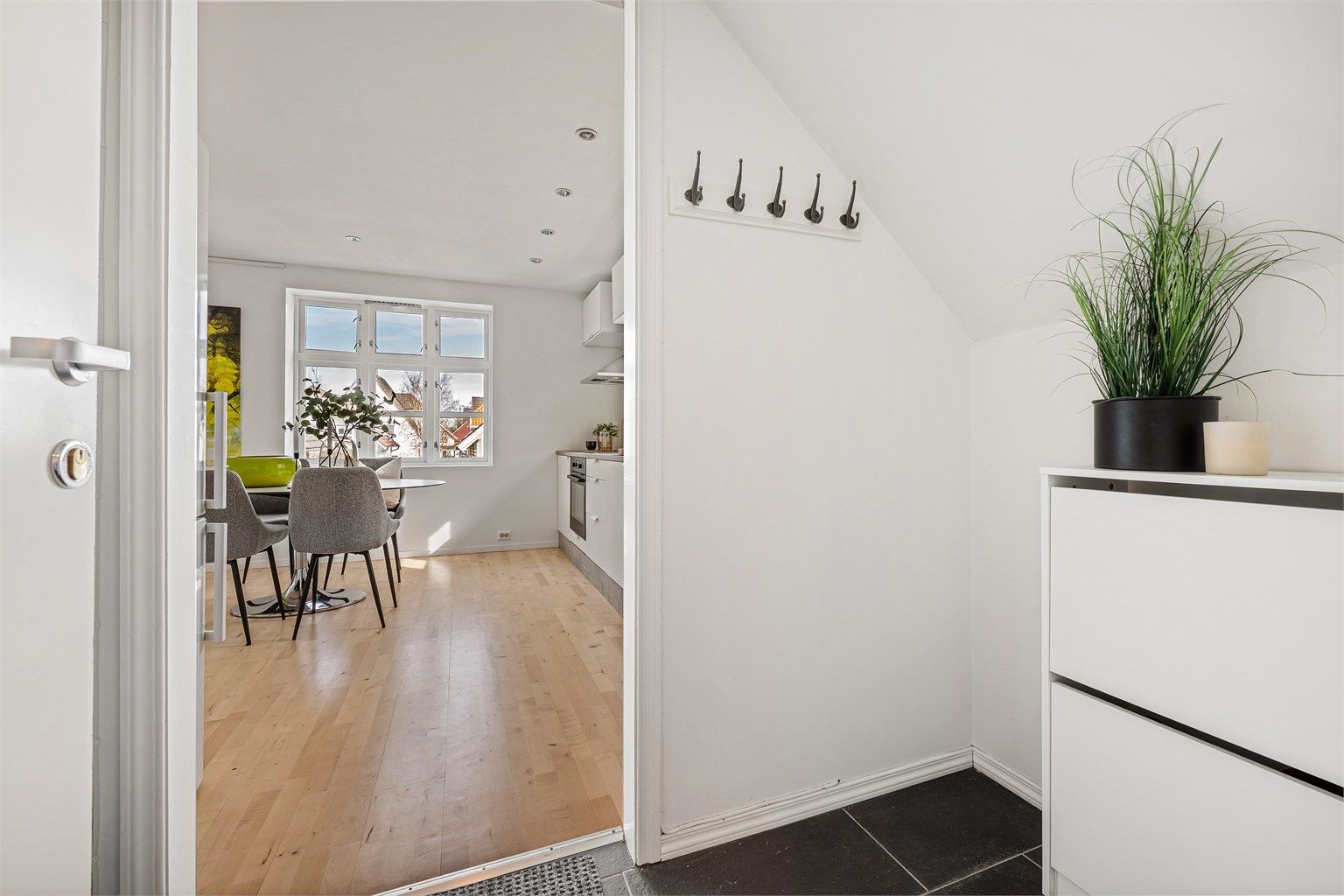 Fra felles inngangsparti med en av de andre leilighetene, kommer man via trapp opp til 2.etg. 
Liten entré med plass til å henge av yttertøy. Fliser på gulv. 